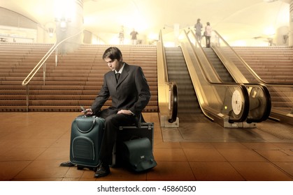 Portrait of a businessman sitting on his luggage in the middle of an airport hall - Powered by Shutterstock