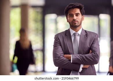 Portrait Of Businessman Standing In Lobby Of Busy Modern Office Building