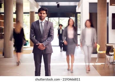 Portrait Of Businessman Standing In Lobby Of Busy Modern Office Building