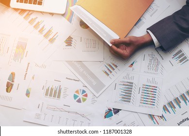 Portrait Of Businessman With Suit Open Brown Envelope For Analysis Business Report On Table In Office With Computer Laptop, He Is Sitting At His Desk, Writing Corporate Documents For His New Project
