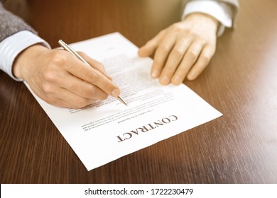 portrait of businessman in suit reading contract documents at the desk in the office.