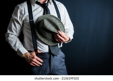 Portrait Of Businessman In White Dress Shirt And Suspenders Holding Old Fedora Hat. Vintage Style And Retro Fashion Of Film Noir Detective.