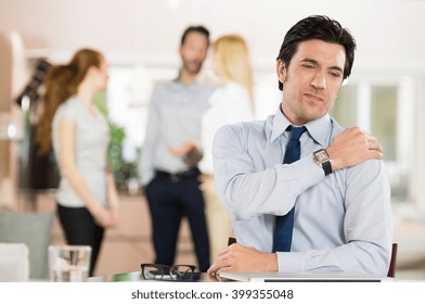Portrait of a businessman at work suffering from shoulder pain. Portrait of stressed man holding shoulder and stretching after work. Mature business man tired and stressed after working for long.
