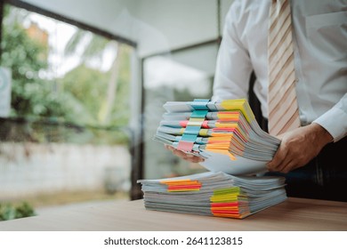 Portrait of businessman working with stack of documents to search for information and check documents on desk in office.