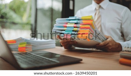 Portrait of businessman working with stack of documents to search for information and check documents on desk in office.