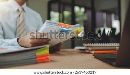 Portrait of businessman working with stack of documents to search for information and check documents on desk in office.
