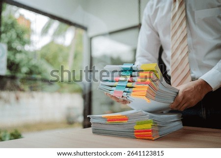 Portrait of businessman working with stack of documents to search for information and check documents on desk in office.