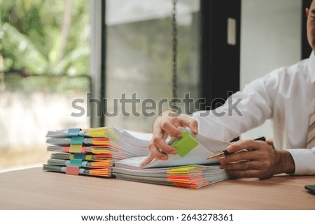 Portrait of businessman working with stack of documents to search for information and check documents on desk in office.
