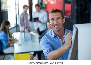 Portrait Of Businessman Writing On Flip Chart In Office