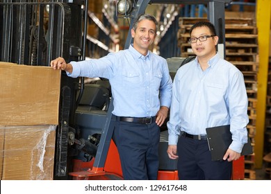 Portrait Of Businessmen With Fork Lift Truck In Warehouse