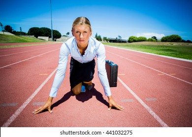 Portrait of businesswoman with briefcase ready to run on running track - Powered by Shutterstock