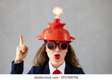 Portrait Of Businesswoman With Lightbulb Against Grey Concrete Wall. Business Start Up And Creative Bright Idea Concept