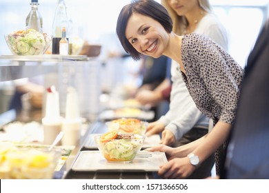 Portrait of businesswoman in lunch line at work cafeteria - Shutterstock ID 1571366506