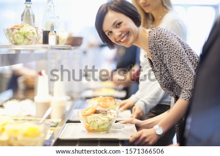 Portrait of businesswoman in lunch line at work cafeteria