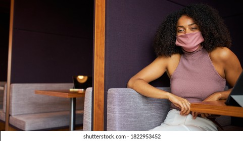 Portrait Of Businesswoman In Mask Working In Socially Distanced Cubicle In Office During Pandemic