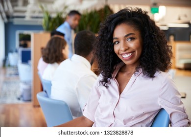 Portrait Of Businesswoman In Modern Office With Colleagues Meeting Around Table In Background