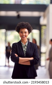 Portrait Of Businesswoman Standing In Lobby Of Busy Modern Office Building