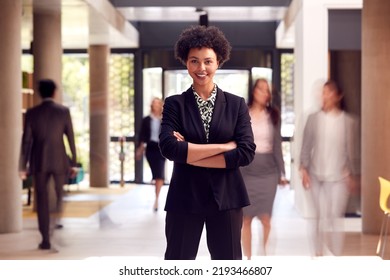 Portrait Of Businesswoman Standing In Lobby Of Busy Modern Office Building