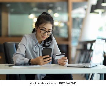 Portrait of businesswoman using smartphone and credit card to online paying on worktable