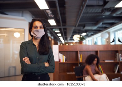 Portrait Of Businesswoman Wearing Face Mask In Modern Open Plan Office During Covid-19 Pandemic