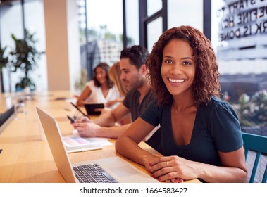 Portrait Of Businesswoman Working At Desk In Shared Open Plan Office Workspace