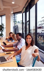 Portrait Of Businesswoman Working At Desk In Shared Open Plan Office Workspace