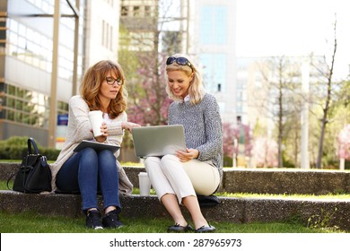 Portrait of businesswomen sitting at office park while using digital tablet and laptop. Business team working online togetherness while consulting.  - Powered by Shutterstock