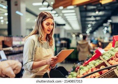 Portrait of a busy female sales assistant in a grocery typing on the tablet while taking inventory - Powered by Shutterstock