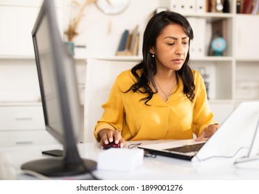 Portrait of busy latin american female office employee working at desk with computer. - Powered by Shutterstock