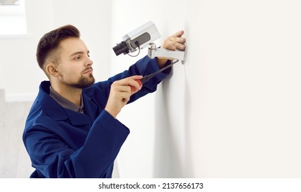 Portrait of busy technician at work. Young man repairing security camera. Male worker using screwdriver while fixing, fitting and adjusting smart CCTV surveillance system in modern office or apartment
