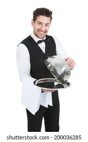 Portrait Of Butler Lifting Cloche From Serving Tray Over White Background