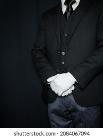 Portrait of Butler or Servant in Dark Suit and White Gloves Standing at Courteous Attention. Concept of Service Industry and Professional Hospitality.