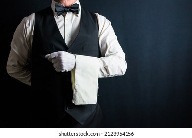 Portrait of Butler or Waiter in Black Vest and White Gloves and Napkin Folded Over His Arm. Service Industry and Professional Hospitality.