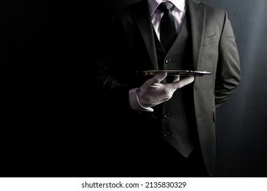 Portrait of Butler or Waiter in Dark Formal Suit and White Gloves Elegantly Holding Silver Serving Tray. Copy Space for Service Industry and Elite Hospitality.