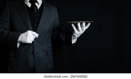 Portrait of Butler or Waiter in Dark Suit and White Gloves Holding Serving Tray on Black Background. Copy Space for Service Industry and Professional Hospitality.