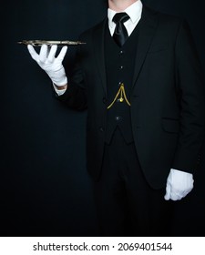 Portrait of Butler or Waiter in Dark Suit and White Gloves on Black Background Holding Silver Serving Tray. Concept of Service Industry and Professional Hospitality.