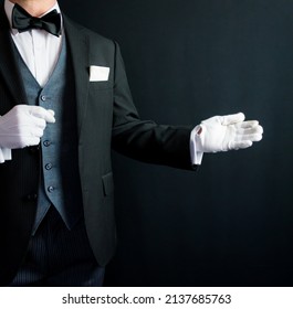 Portrait Of Butler With Welcoming Gesture In Formal Suit And White Gloves. Service Industry And Professional Courtesy. 