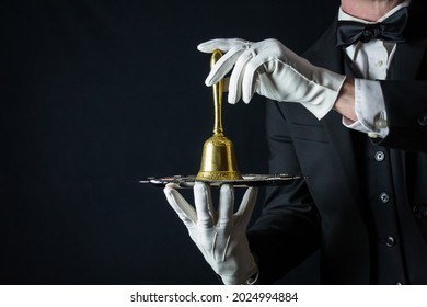 Portrait of Butler in White Gloves and Dark Suit Holding Gold Bell on Silver Tray. Copy Space for Service Industry and Professional Hospitality.