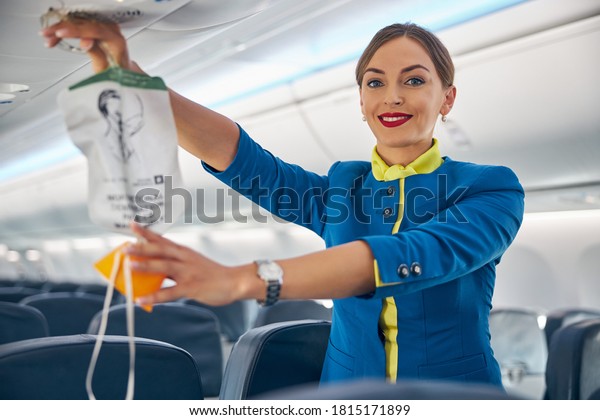 Portrait of cabin crew holding up the oxygen\
mask during the safety demonstration on board commercial\
international airlines
