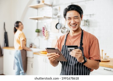 Portrait Of A Cafe SME Owner Male Entrepreneurs Feeling Happy. He Holding An IPad And Credit Card On Hand. A Loan To Do Business. Order Online With Credit Cards.