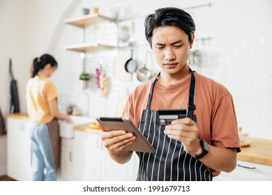 Portrait Of A Cafe SME Owner Male Entrepreneurs Feeling Stressed. He Holding An IPad And Credit Card On Hand. A Loan To Do Business. Order Online With Credit Cards.