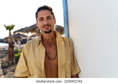 Portrait of calm handsome hippie italian man with smile looking at the camera, relaxing on the beach. Wanderlust. Tropics. Traveler. Relax. Tourism.