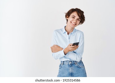 Portrait Of Candid Happy Woman Smiling, Using Smartphone And Looking At Camera, Standing Over White Background. Copy Space