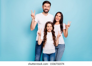 Portrait of candid three people promoters hug embrace have brunet hair make v-signs wear white t-shirt denim jeans casual outfit isolated over blue color background