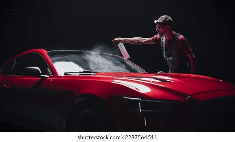 Portrait of a Car Detailer Spreading a Chemical Wax Solution for Polishing a Windshield and Protecting the Glass from Steaming Up During the Rain. Red Sports Car Serviced at a Detailing Studio