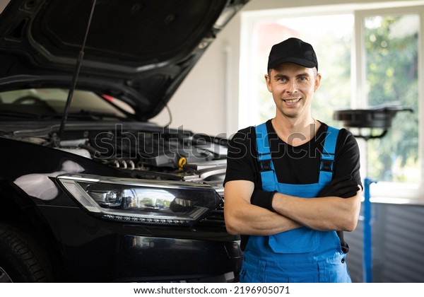 Portrait of\
car mechanic crossed arms in car workshop of service background .\
Concept: repair of machines, fault diagnosis, repair specialist,\
technical maintenance and on-board\
computer.