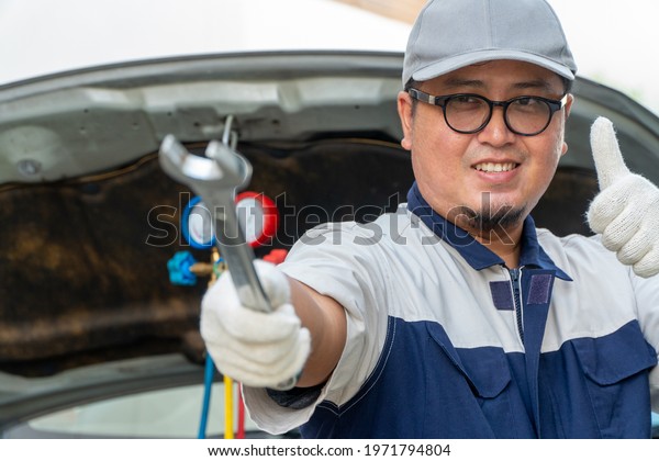 Portrait of a car mechanic\
holding a wrench at an automobile repair shop. Concept of repair of\
machines