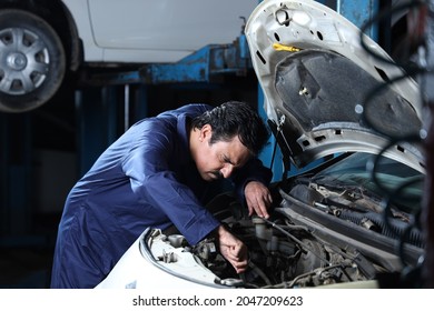 Portrait of a car mechanic in moustache repairing and examining the car engine. Car specialist is using repairing tools. Repairman wearing a mechanic uniform in blue working very hard and dedicatedly. - Shutterstock ID 2047209623