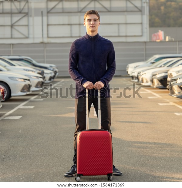 Portrait of a car rental customer with\
a red suitcase. The concept of renting a\
vehicle