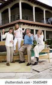 Portrait Of Carefree Family Of Four Playing Air Guitar On Patio